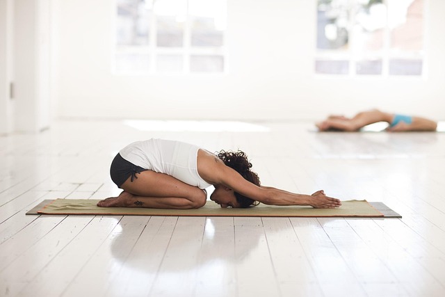person practicing yoga at home following an online class on laptop screen with natural light